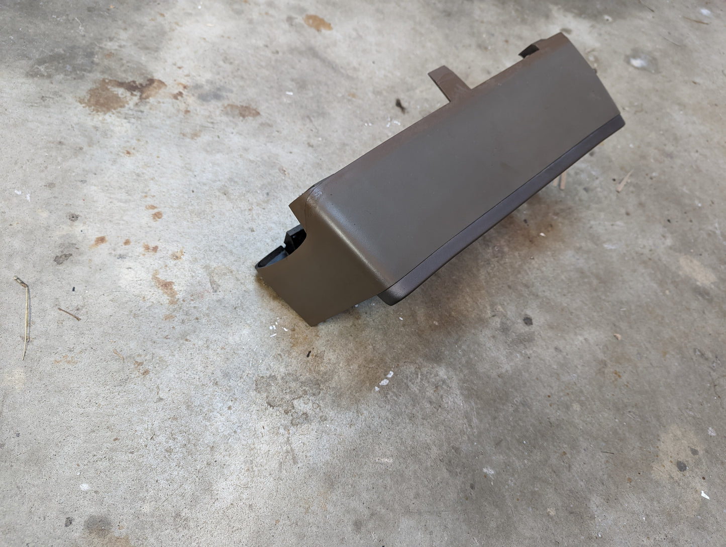 A General Motors OEM tan instrument cluster dash bezel for 1986-1993 Chevy S10, Blazer, GMC S15, and more lies on a stained concrete floor.