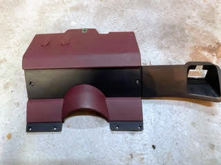 A red OEM Lower Dash Trim Knee Bolster by General Motors for 1986-1993 Chevy S10, Blazer, GMC S15, and more is shown on a light-colored, textured surface.