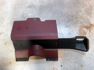 A red OEM Lower Dash Trim Knee Bolster by General Motors for 1986–1993 Chevy S10 Blazer, GMC S15, and more, featuring a curved lower opening and rectangular side chute, is shown resting on a concrete floor.