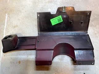A red OEM Lower Dash Trim Knee Bolster by General Motors for 1986-1993 Chevy S10 Blazer, GMC S15, and more features a rectangular section, curved cutout, raised left area, and green label on top. Its shown resting on concrete.