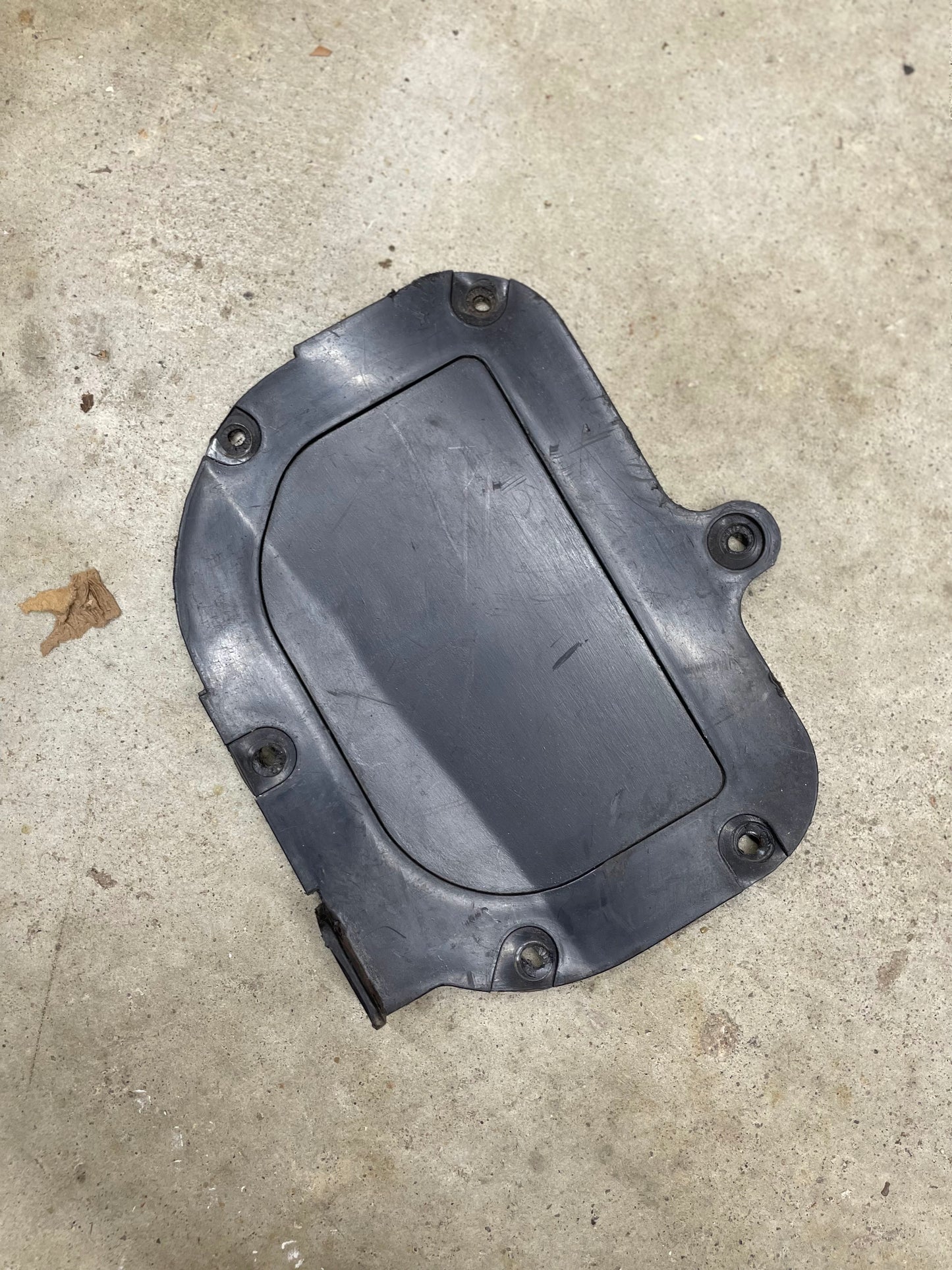 A General Motors OEM Fresh Air Block-Off Panel for 1982–1993 Chevrolet S10 and Blazer, made of black plastic or rubber with five mounting holes, a rectangular shape, rounded edges, and a raised border is shown on a concrete floor.
