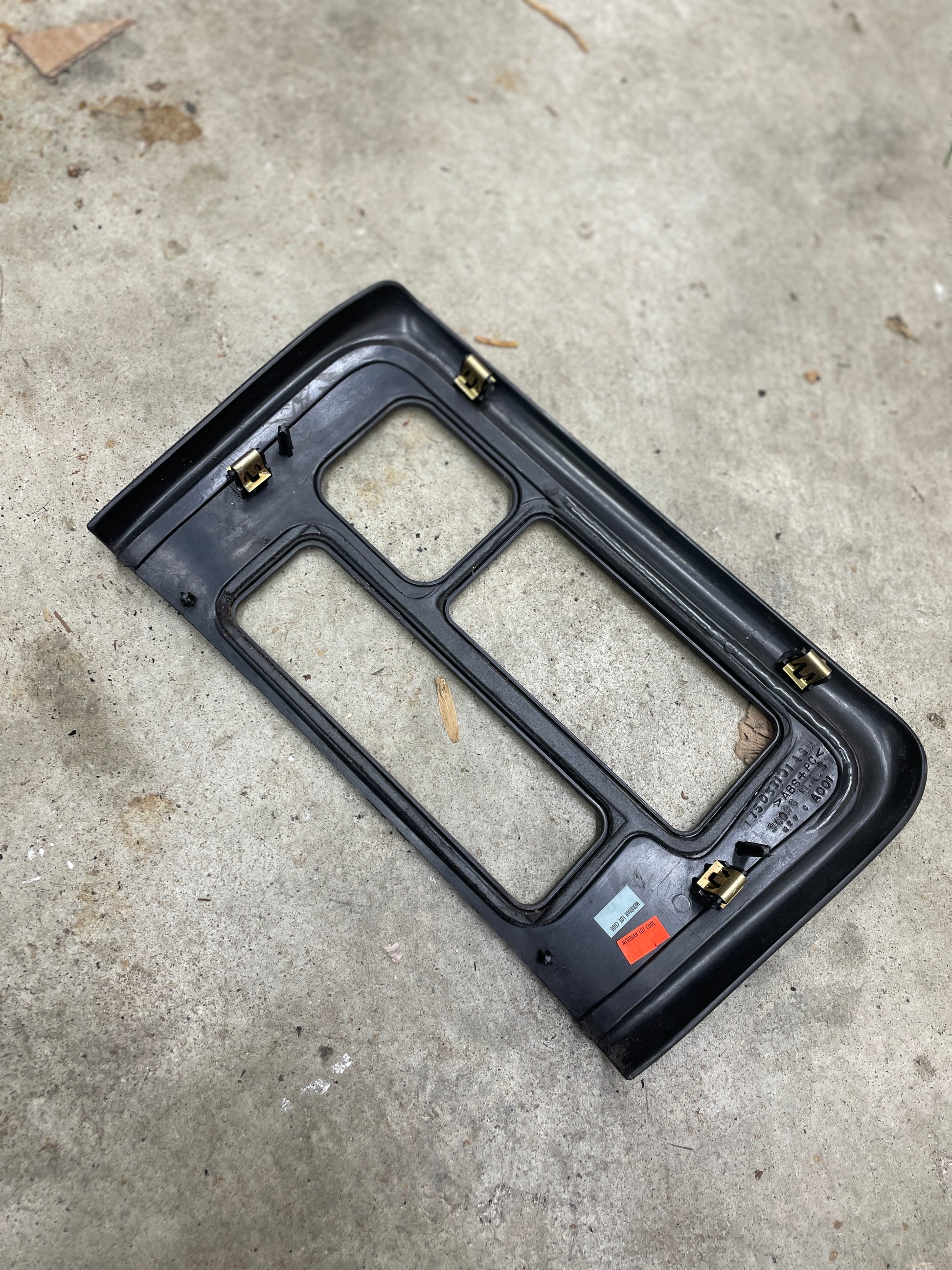 A General Motors OEM Center Console Front Bin with Dark Woodgrain Trim for 2001-2002 GMC Sierra C3 and Yukon Denali is shown on a concrete surface, featuring labels identifying the product name and fitment.