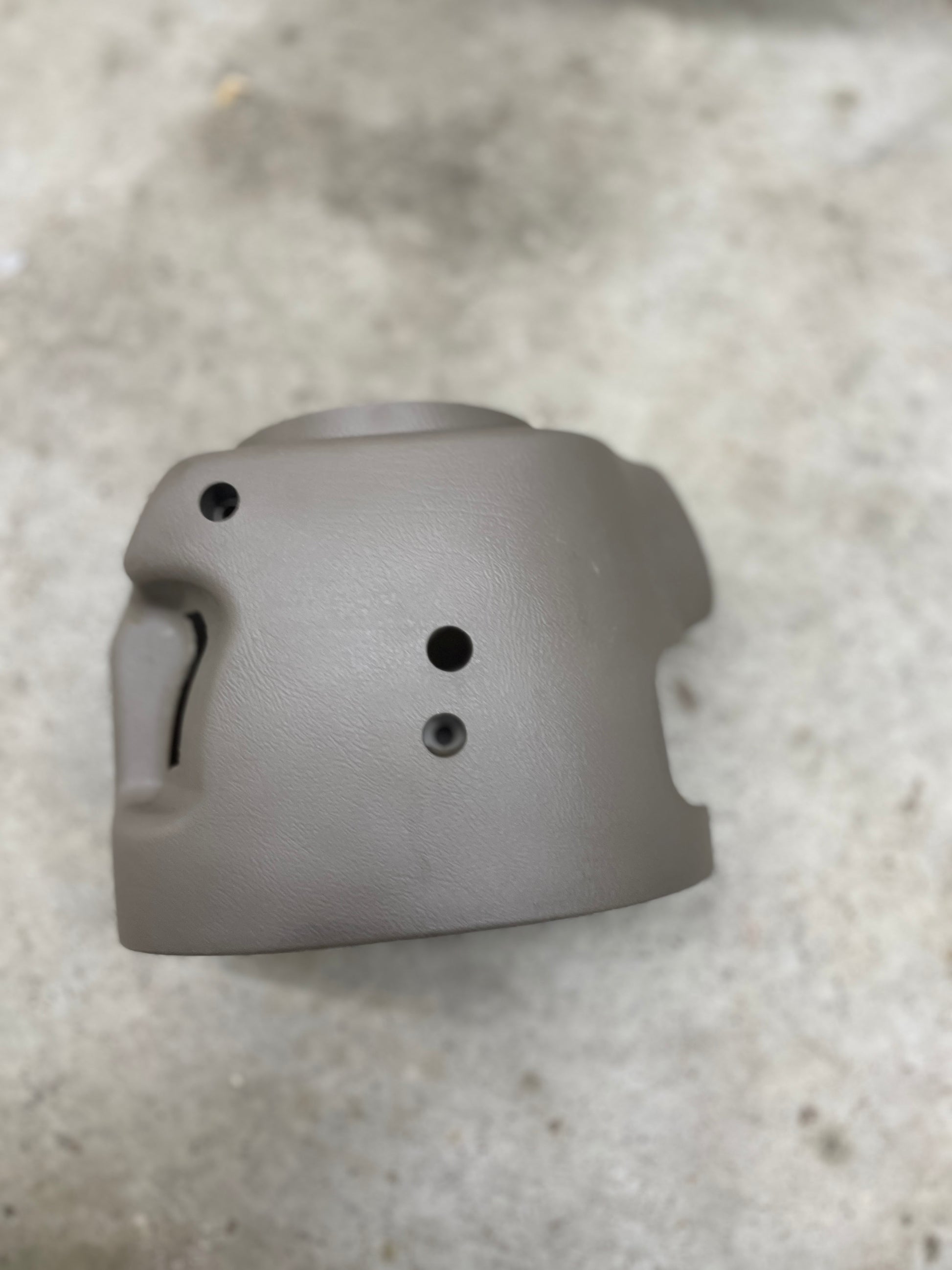 A SET Steering Column Shift Cover w/Automatic Transmission in Beige by General Motors for 2001-2002 GMC Denali, Cadillac Escalade, and more is shown in close-up on a light concrete surface.