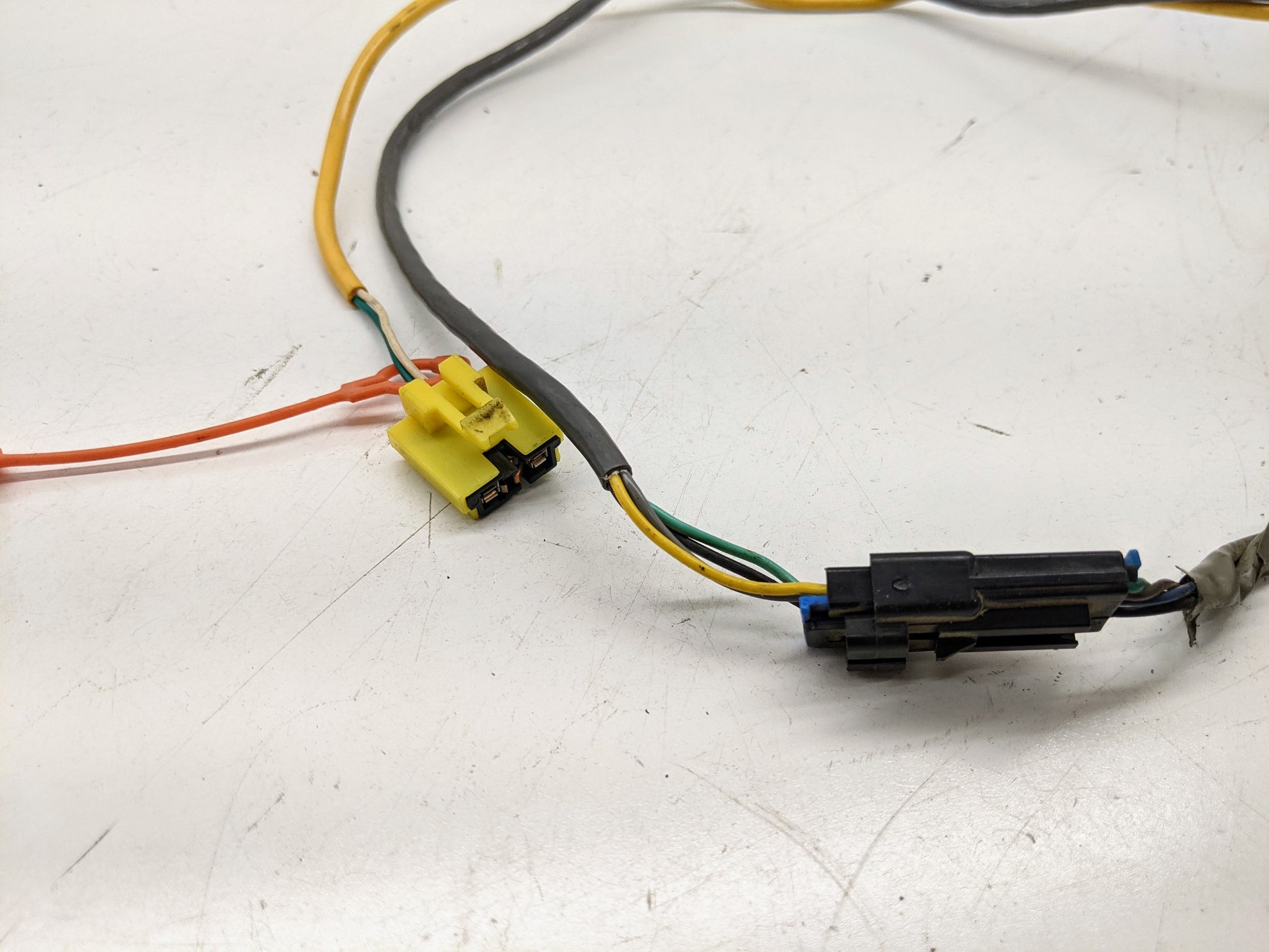 Close-up of General Motors OEM Steering Wheel SRS Air Bag Clock Spring with radio controls, showing orange, yellow, black, green, and blue wires for 2000-2003 Chevy S10 Blazer on a white surface; unit is tested.