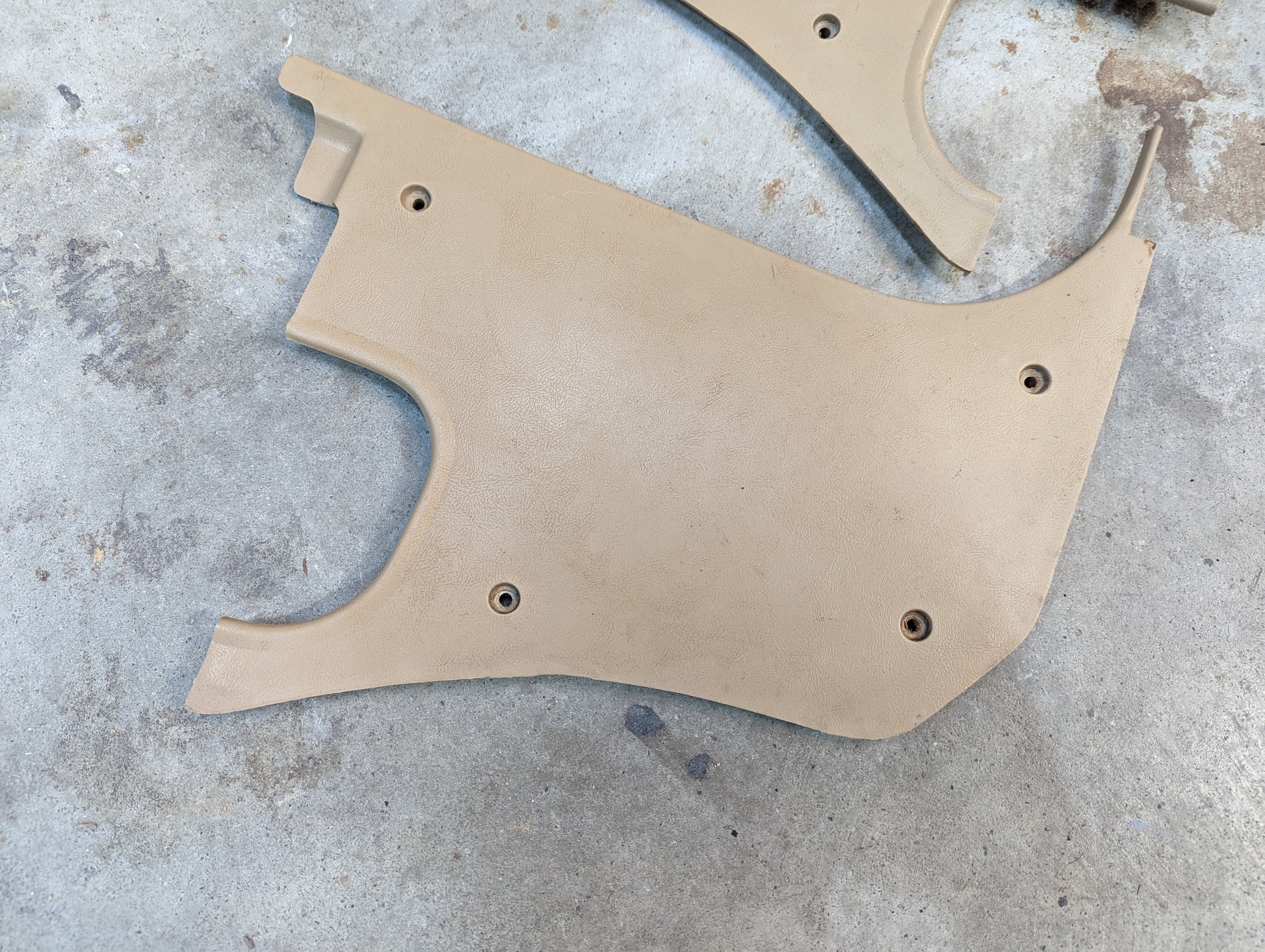 A tan OEM Pair Kick Panel Knee Trim by General Motors, featuring Beige 64I trim and screw holes, fits 1982-1993 Chevrolet S10, Blazer, and more—perfect replacement panels with curved edges for your truck’s interior.