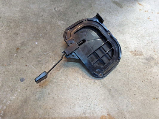 A black OEM Fresh Air Floor Vent Door Driver-Side LH by General Motors, made of plastic with a grid pattern and lever arm, sits on concrete; fits 1982-1993 Chevrolet S10, Blazer, and similar models’ vent door assemblies.