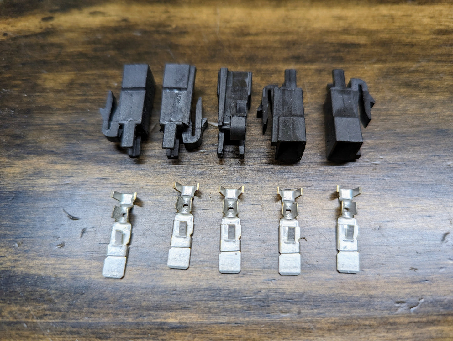 Five Aptiv KIT Power Tap Connectors & Terminals for Under Dash Fuse Panel—designed for many 80s & 90s vehicles—are arranged in two rows on wood, perfect for classic car wiring upgrades.