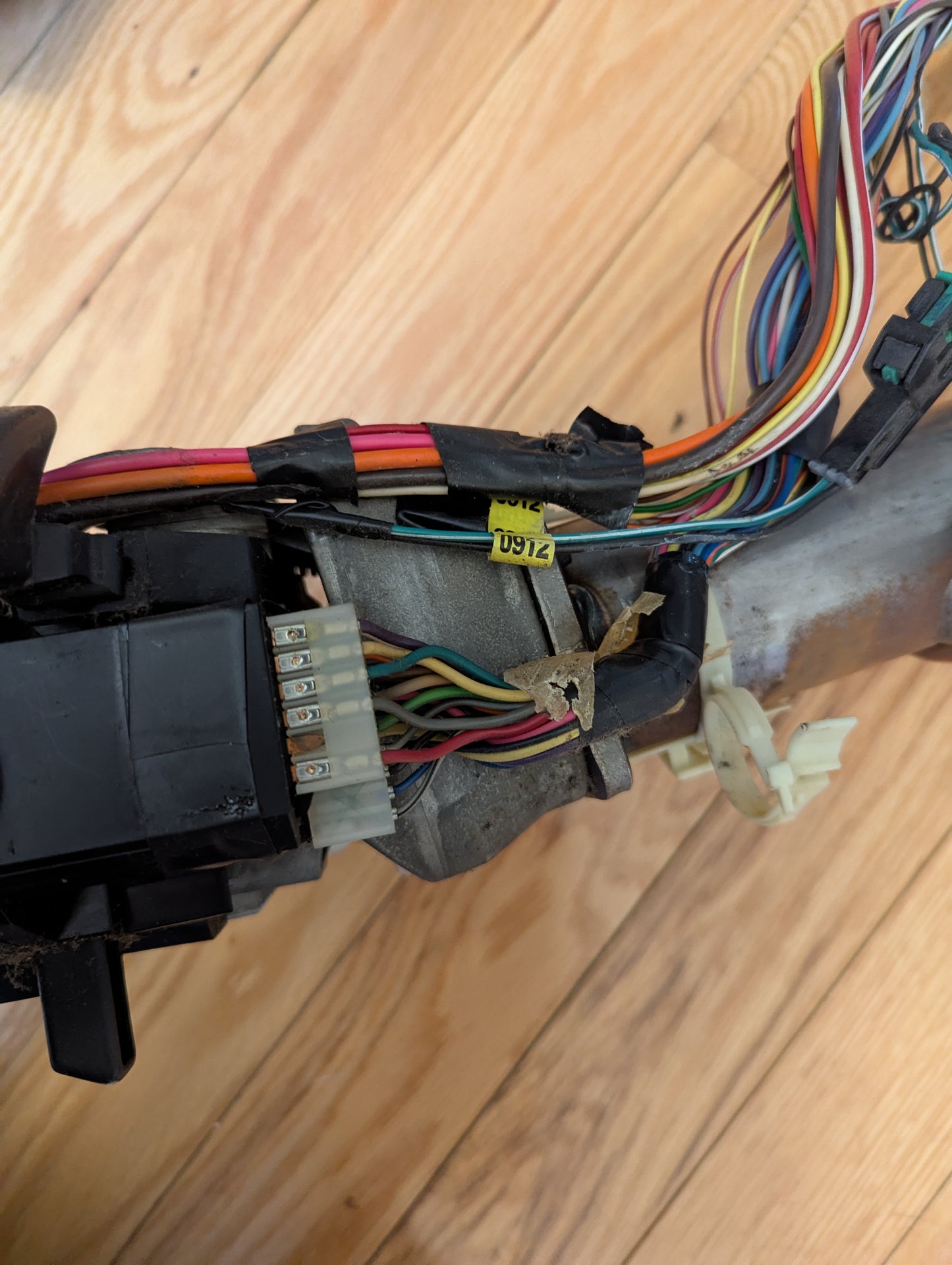 Close-up of a General Motors OEM Steering Column with tilt, cruise control, and console shift for 1998-2005 Chevy S10 Blazer, showing exposed wiring and connectors on a wooden floor.