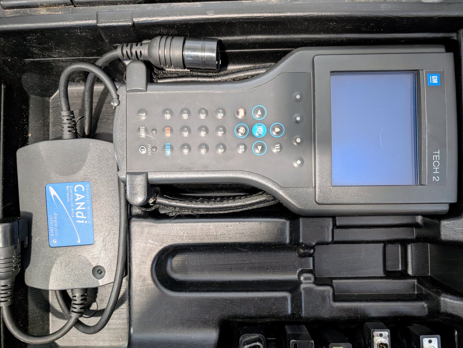 The Vetronix TESTED Tech 2 Automotive Diagnostic Tool & Accessories for 1991-2013 GM Vehicles, with blue screen and CANDi module, sits in a carrying case—an essential GM diagnostic tool.