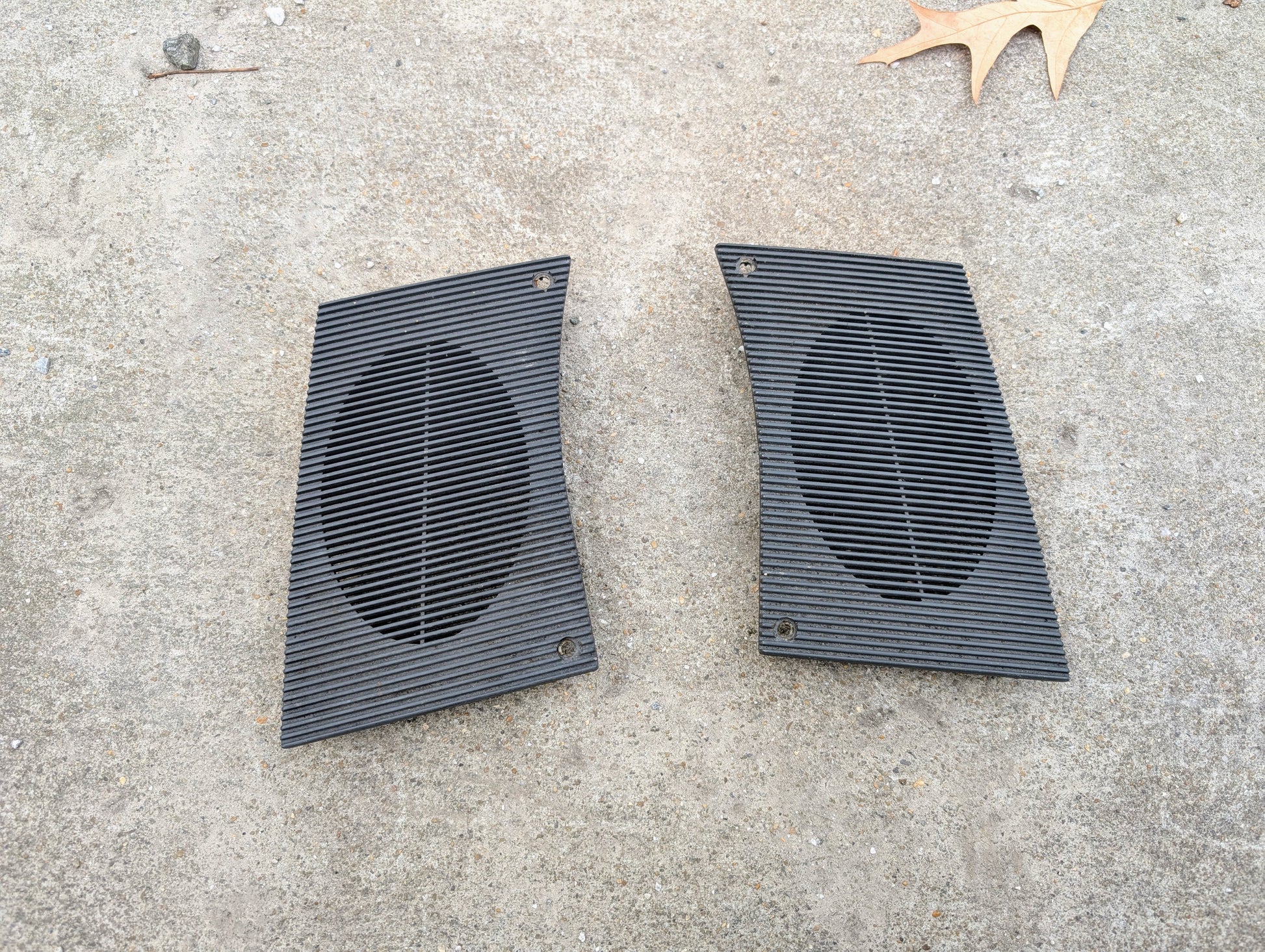 Two black speaker Grilles on a concrete surface