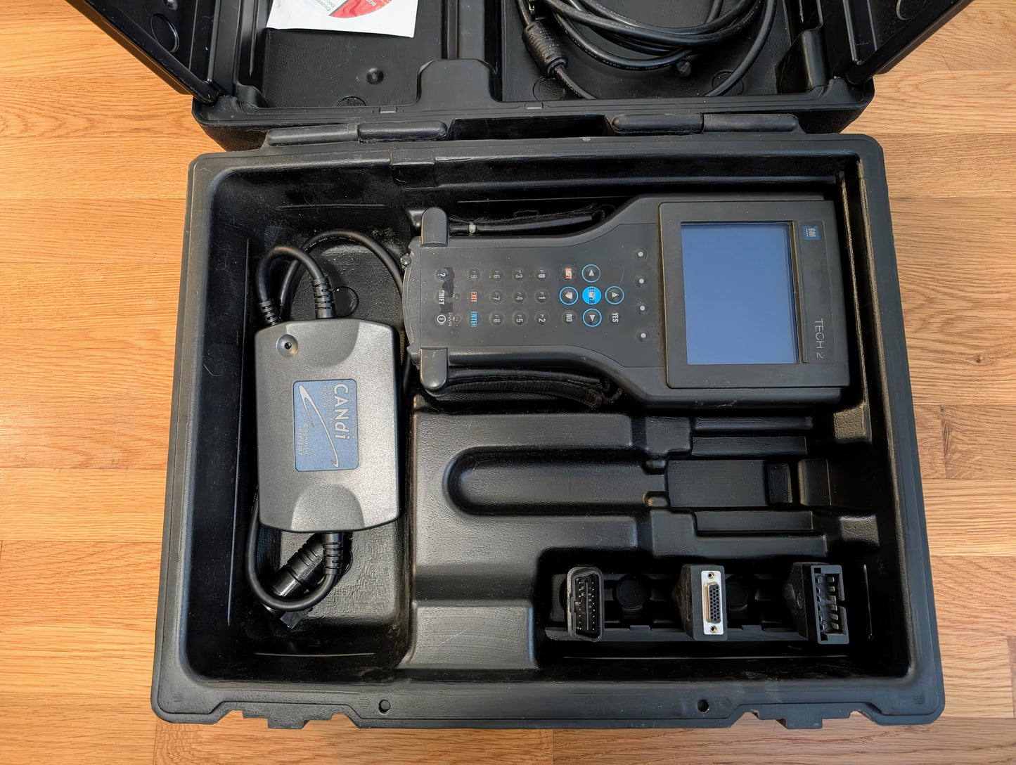 The Vetronix TESTED Tech 2 Automotive Diagnostic Tool & Accessories for 1991-2013 GM Vehicles is shown with a screen and buttons in a black carrying case, plus cables and connectors—ideal as an OBD2 Code Scanner for GM diagnostics.