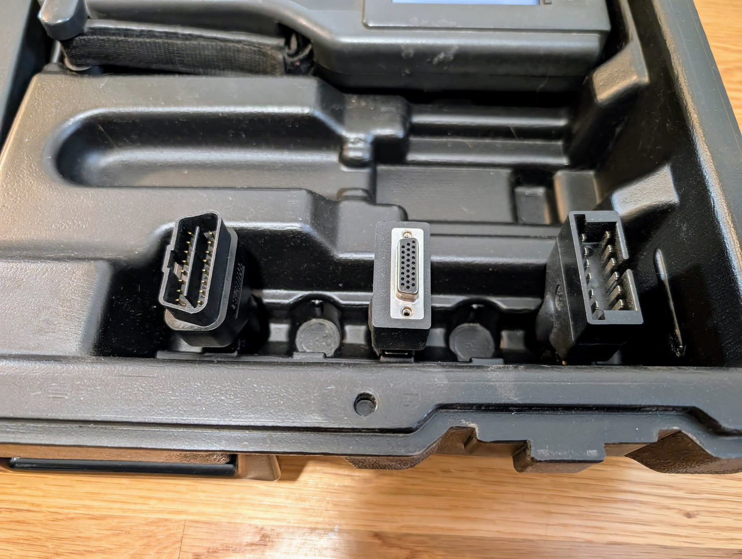 Three Vetronix TESTED Tech 2 Automotive Diagnostic Tool connectors for 1991-2013 GM vehicles are displayed in a black, slotted plastic case. Each connector features a distinct shape and pin configuration, visible from above on a wooden surface.