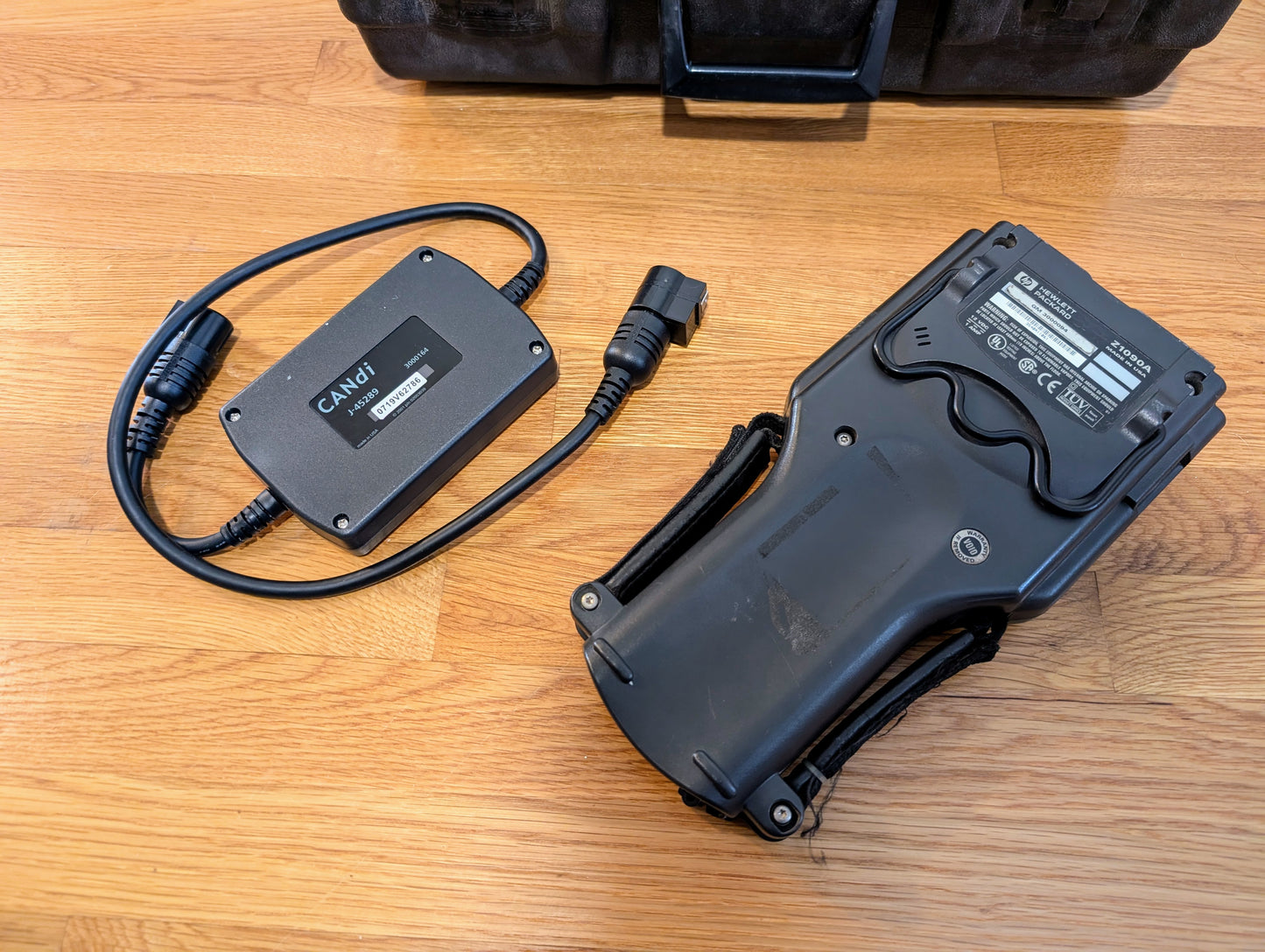 A rugged black Vetronix TESTED Tech 2 Automotive Diagnostic Tool & Accessories for 1991-2013 GM vehicles with a screen and handle rests near a CANDI OBD2 scanner cable and case—ideal for any GM dealer or professional technician.