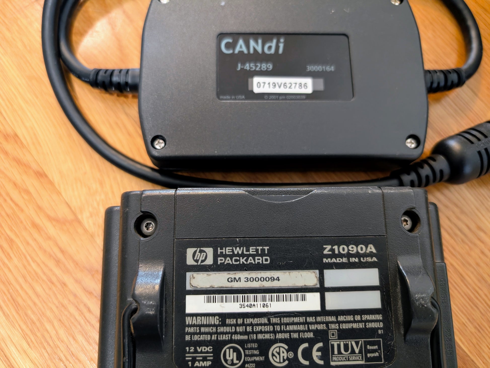 Two black Vetronix Tech 2 Automotive Diagnostic Tool & accessories for 1991-2013 GM vehicles rest on a wooden surface, displaying model/serial numbers and certification labels—ideal OBD2 scanner equipment for GM diagnostics.