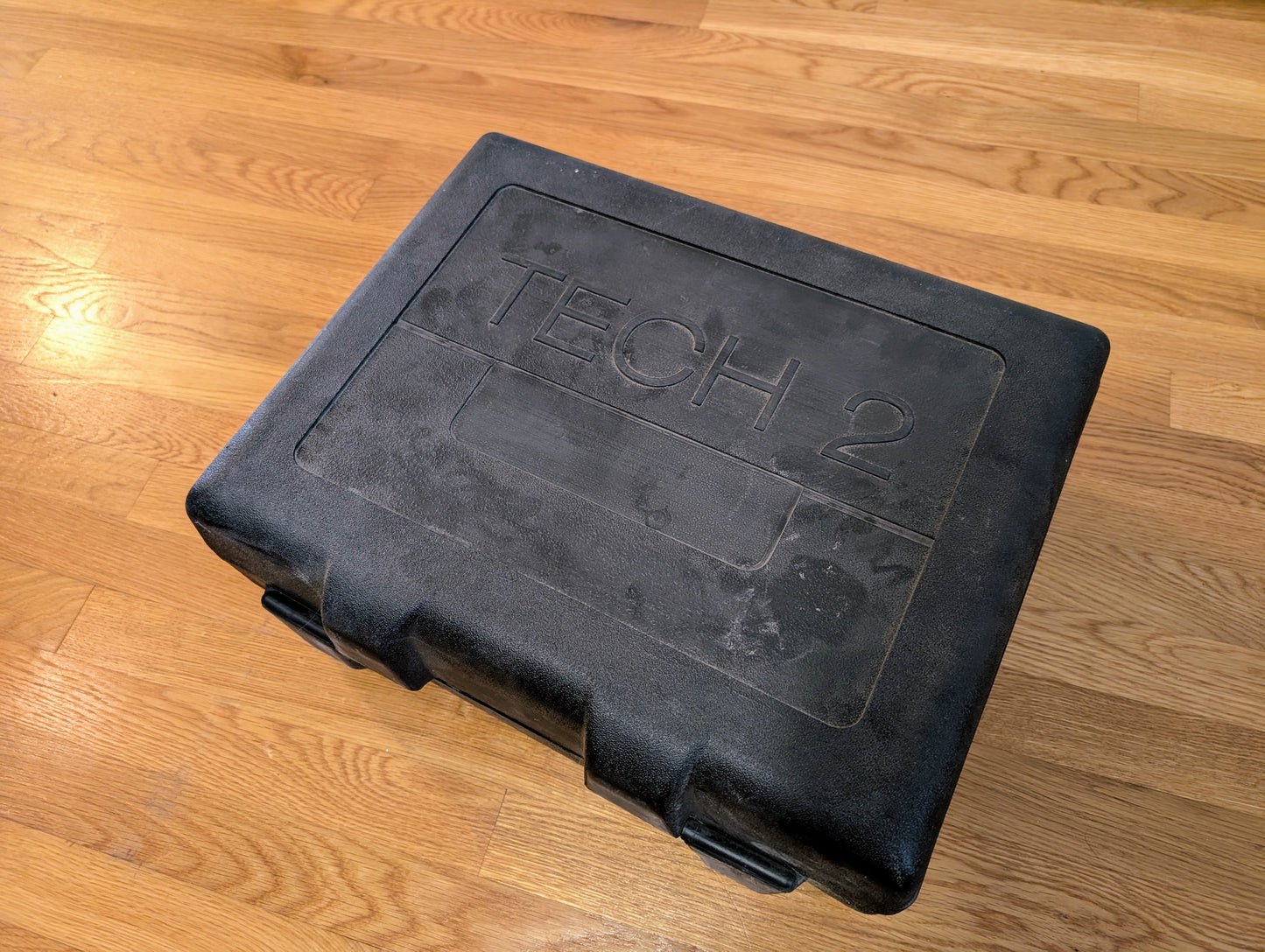 A black hard plastic carrying case labeled TECH 2, for the Vetronix TESTED Tech 2 Automotive Diagnostic Tool & Accessories (1991-2013 GM Vehicles), sits closed on a wooden floor.