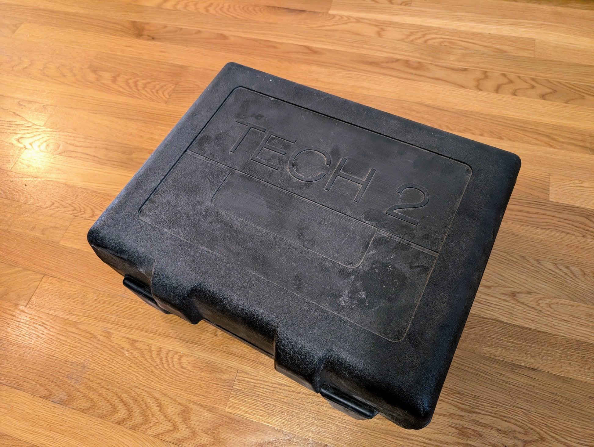 A black hard plastic carrying case labeled TECH 2, for the Vetronix TESTED Tech 2 Automotive Diagnostic Tool & Accessories (1991-2013 GM Vehicles), sits closed on a wooden floor.
