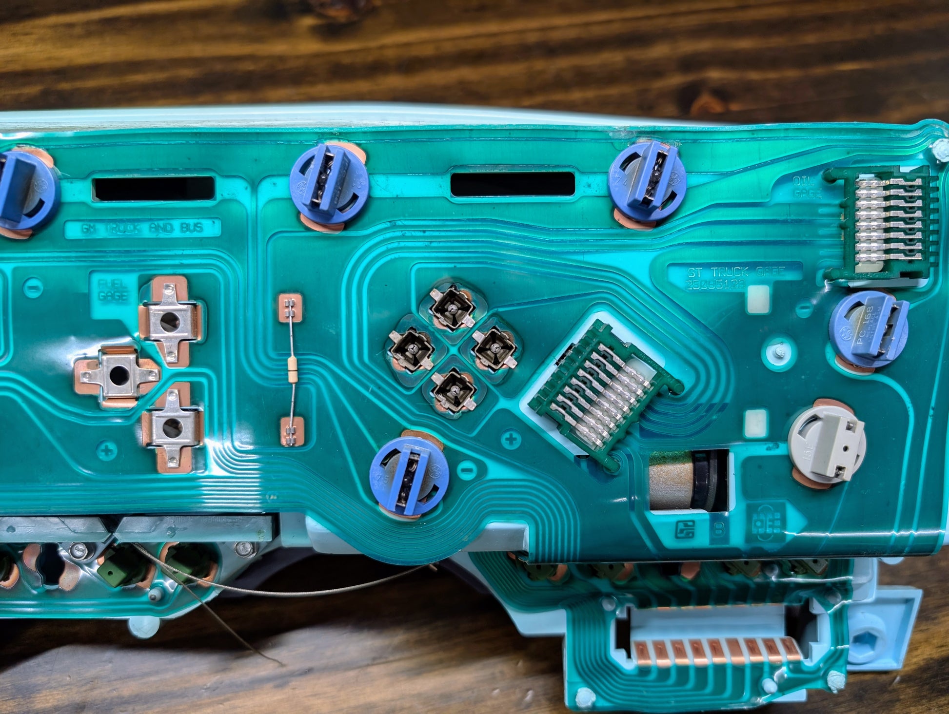 Close-up of a General Motors OEM Instrument Cluster with PRNDL and 110 mph speedo for 1986-1994 Chevy S10 Blazer, showing green PCB, copper traces, connectors, and blue screw covers typical of analog clusters from this era.