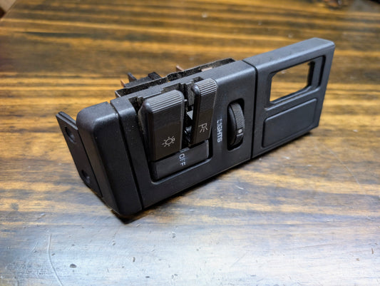 Close-up of a General Motors OEM Headlight Headlamp Switch in black for 1986-1994 Chevy S10, Blazer, GMC S15, and Jimmy on a wooden surface.
