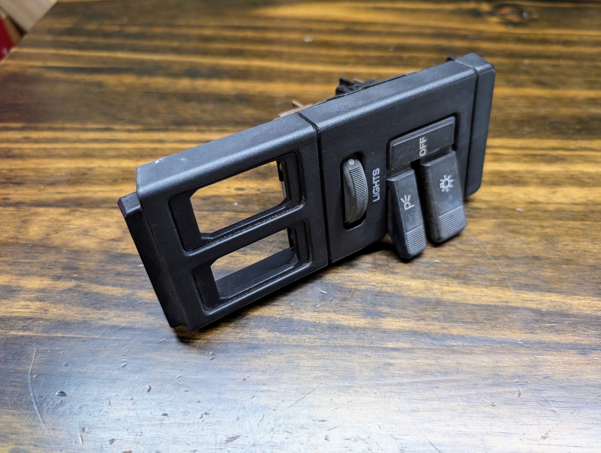 A General Motors OEM black headlight/headlamp switch panel for 1986-1994 Chevy S10, Blazer, GMC S15, and Jimmy, featuring labeled controls and two empty slots for dome override or OEM dimmer switches.