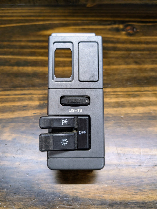 A black OEM Headlight Headlamp Switch by General Motors, featuring labeled LIGHTS and OFF sliders with a top cutout, designed for 1986-1994 Chevy S10, Blazer, GMC S15, and Jimmy models.
