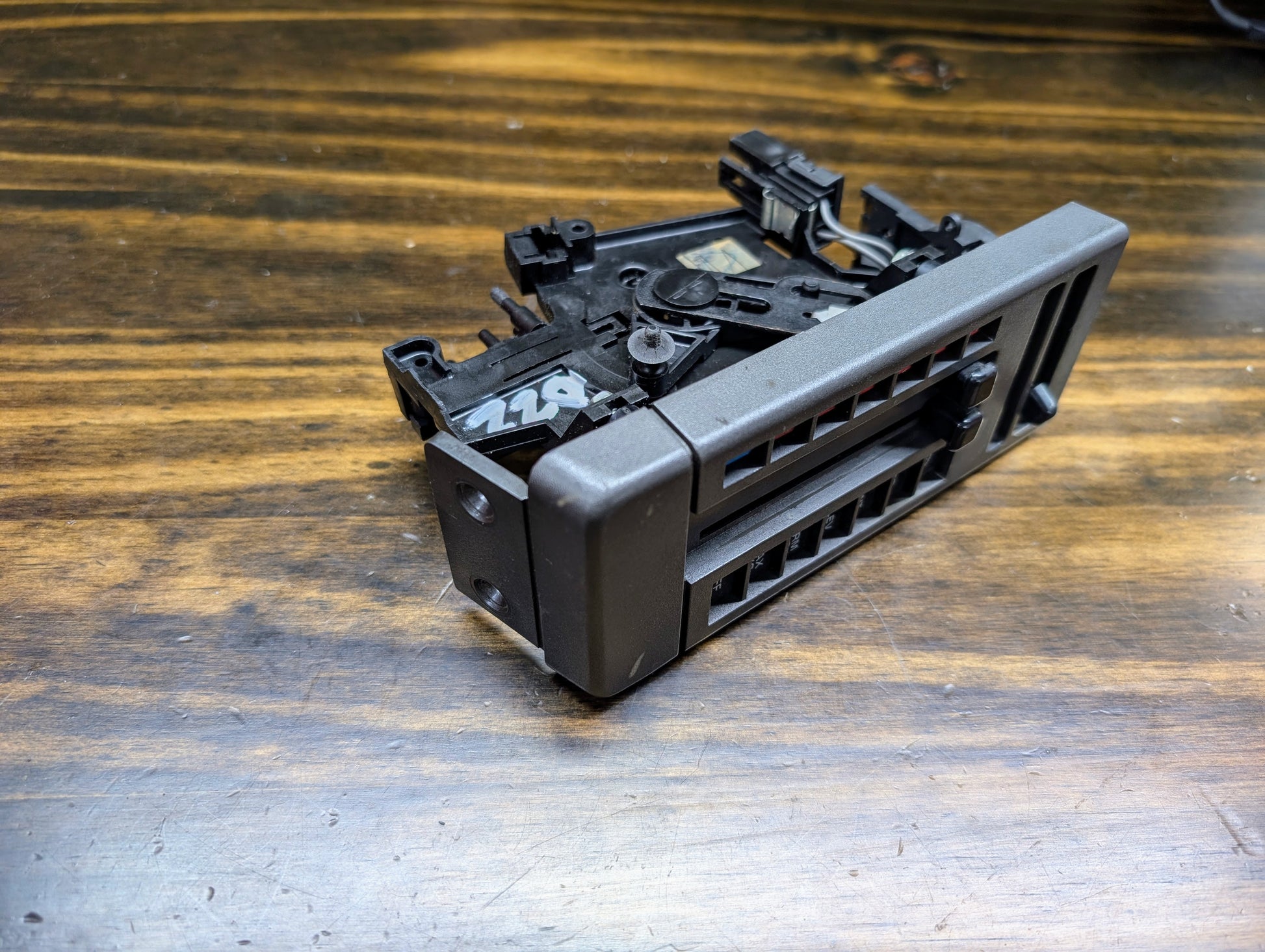 A used General Motors HVAC Heater Control Panel with A/C for 1986-1994 Chevrolet S10, Blazer, and more is shown on a wooden surface. The black unit has adjustment levers and 226 marked in white.