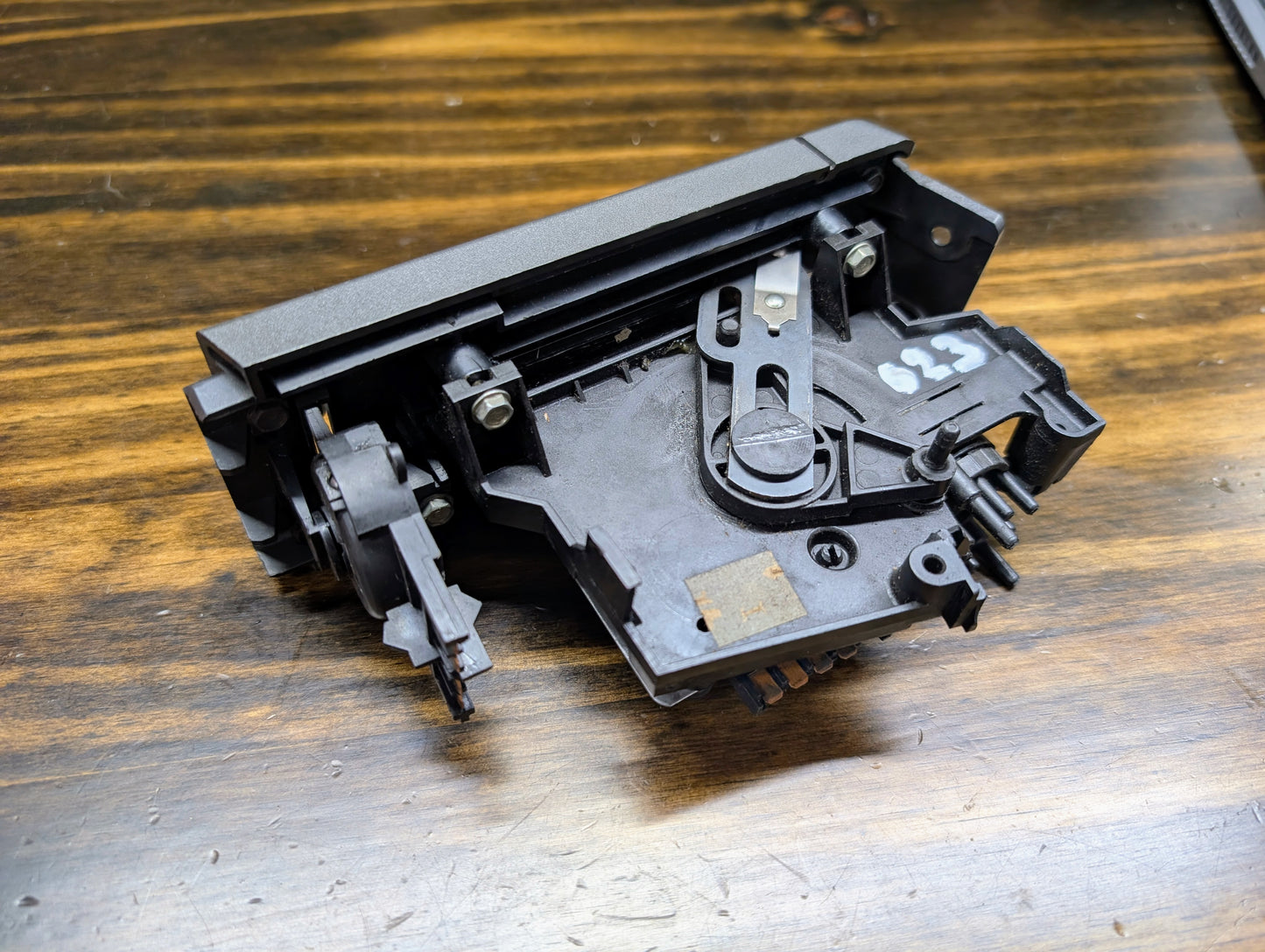 A close-up of a General Motors HVAC Heater Control Panel with A/C for 1986–1994 Chevrolet S10 and Blazer, showing metal parts and screws on wood. The number 623 is written in white on the right side of this black control panel.