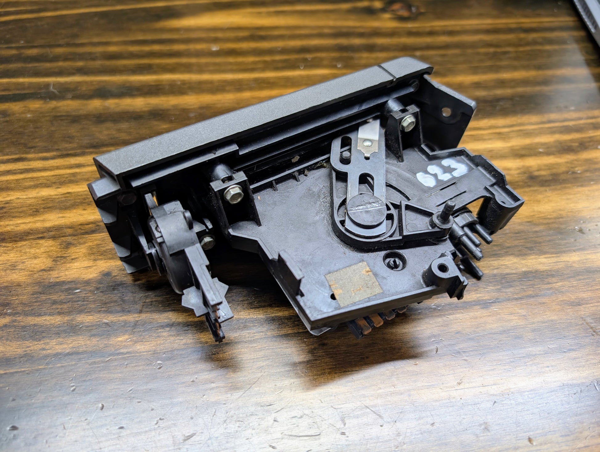 A close-up of a General Motors HVAC Heater Control Panel with A/C for 1986–1994 Chevrolet S10 and Blazer, showing metal parts and screws on wood. The number 623 is written in white on the right side of this black control panel.