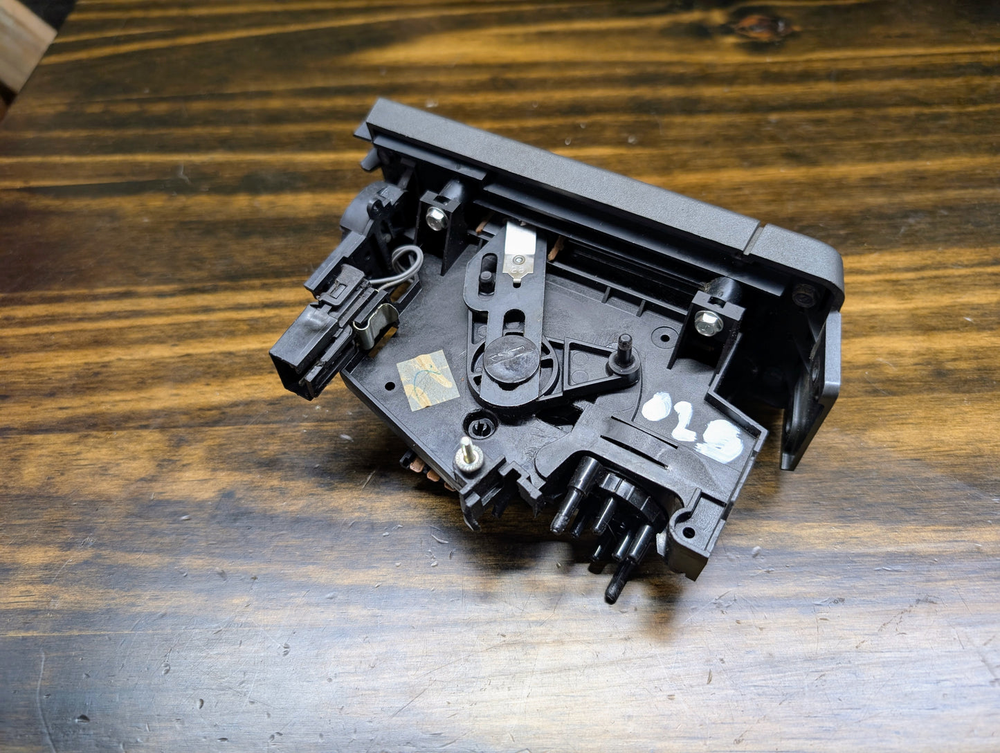 A black plastic General Motors HVAC Heater Control Panel with A/C for 1986-1994 Chevrolet S10, Blazer, and more is shown on a wooden surface.