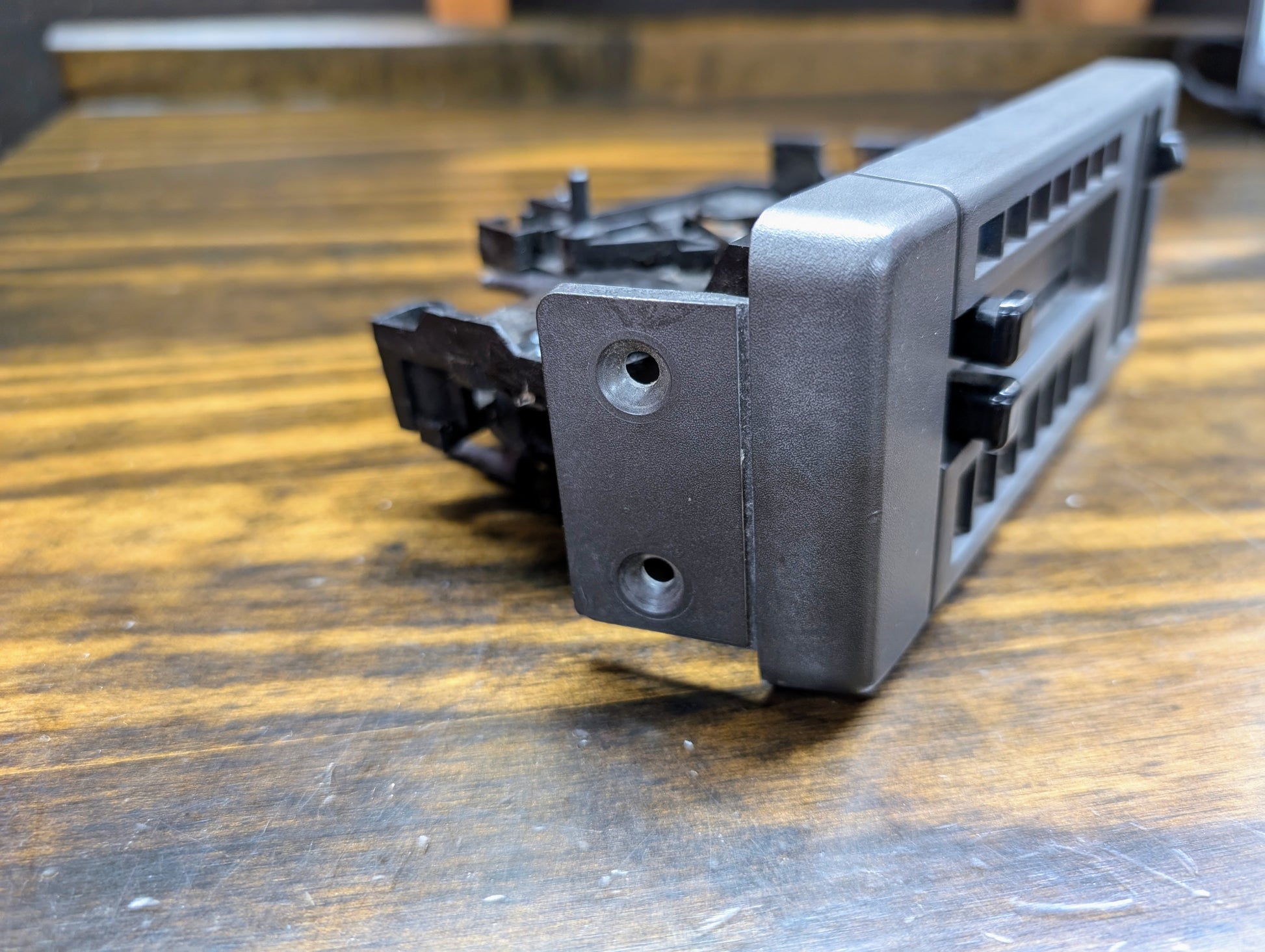 A General Motors HVAC Heater Control Panel with A/C for 1986-1994 Chevrolet S10 and Blazer rests on a wooden surface, angled to show its mounting holes.