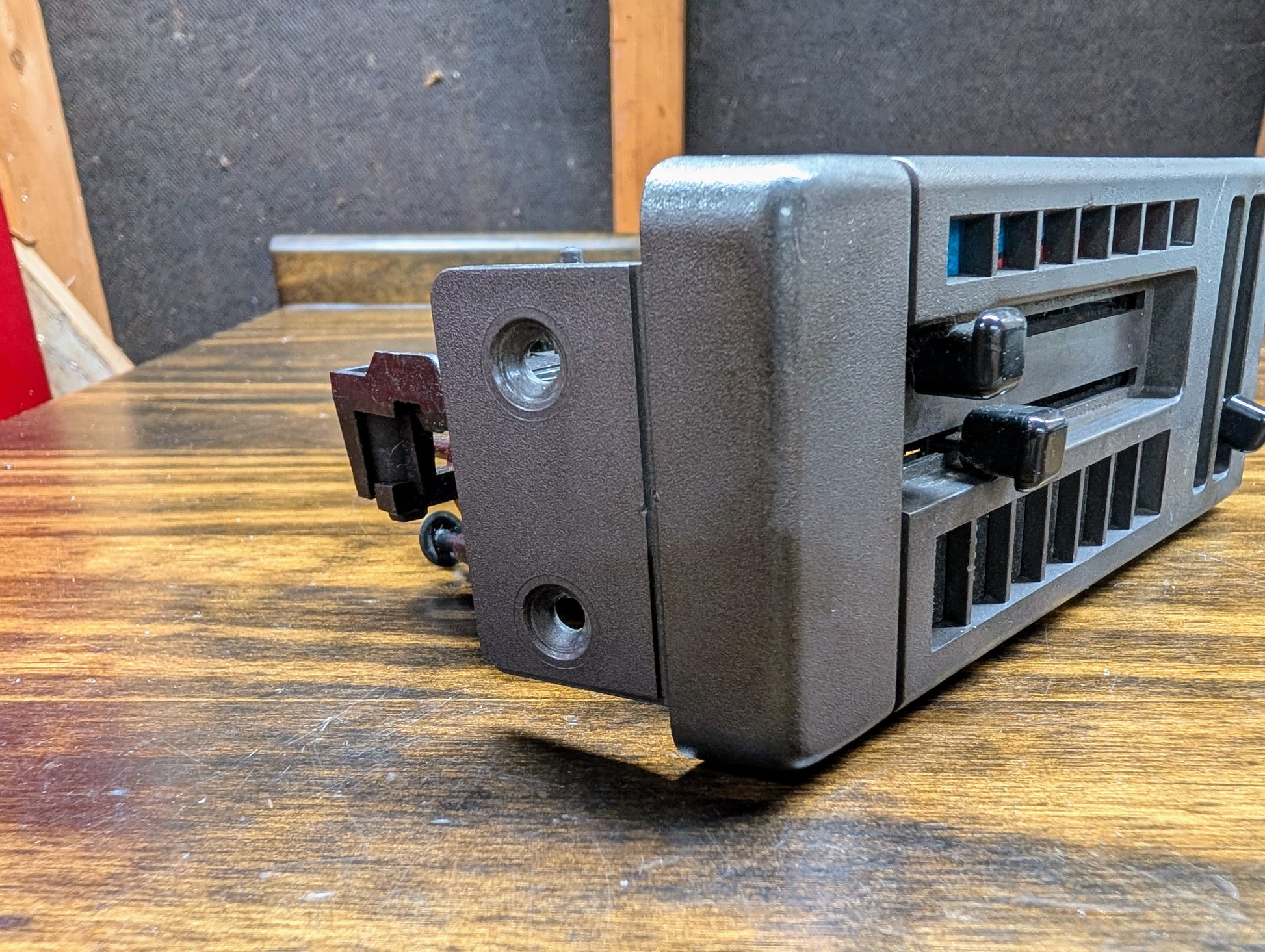 A close-up of a General Motors HVAC Heater Control Panel with A/C for 1986-1994 Chevrolet S10, Blazer, and more, showing the black plastic assembly with grille openings and mounting brackets on a wooden surface.