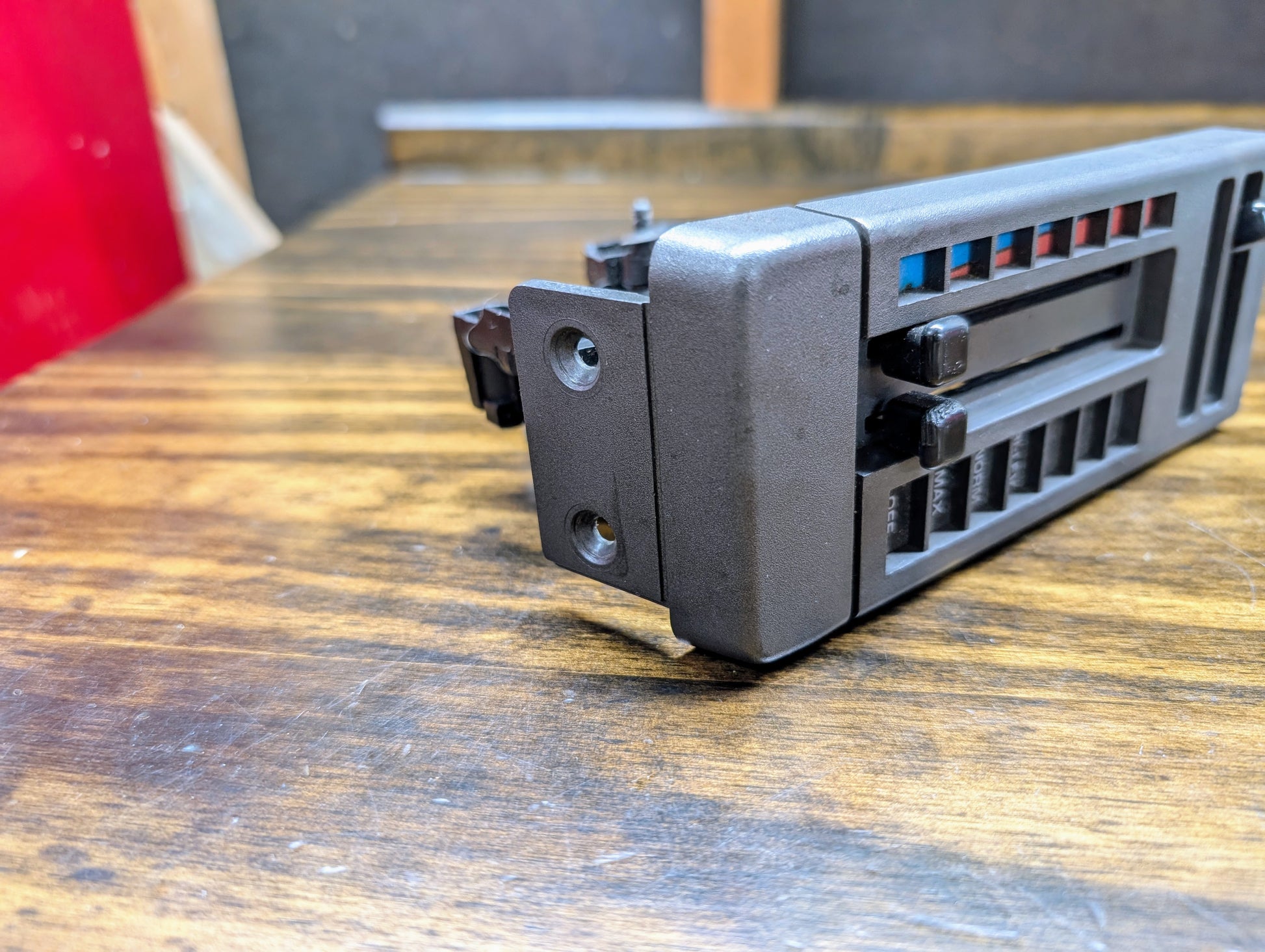 Close-up of a black General Motors HVAC Heater Control Panel with A/C for 1986-1994 Chevrolet S10 and Blazer, showing air flow control sliders and mounting holes on a wooden surface.