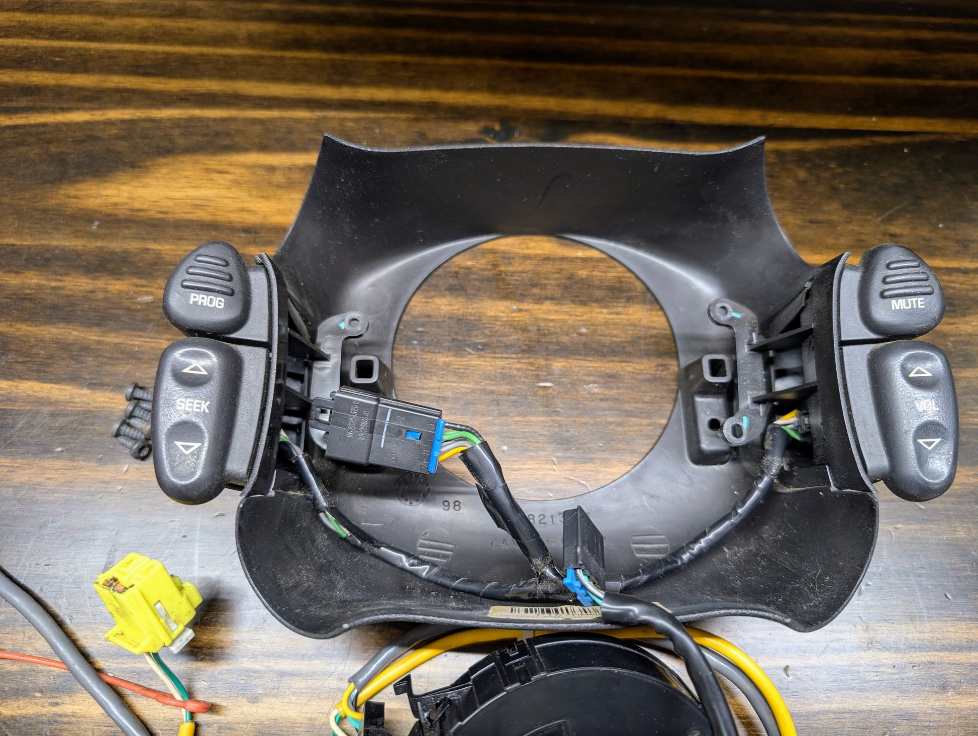 Close-up of General Motors KIT Steering Wheel Black Button Radio Controls & Clock Spring for 2004-2005 Chevy S10/Blazer, showing “PROG,” “SEEK,” “MUTE,” and “VOL” on a black module with exposed wires and connectors.