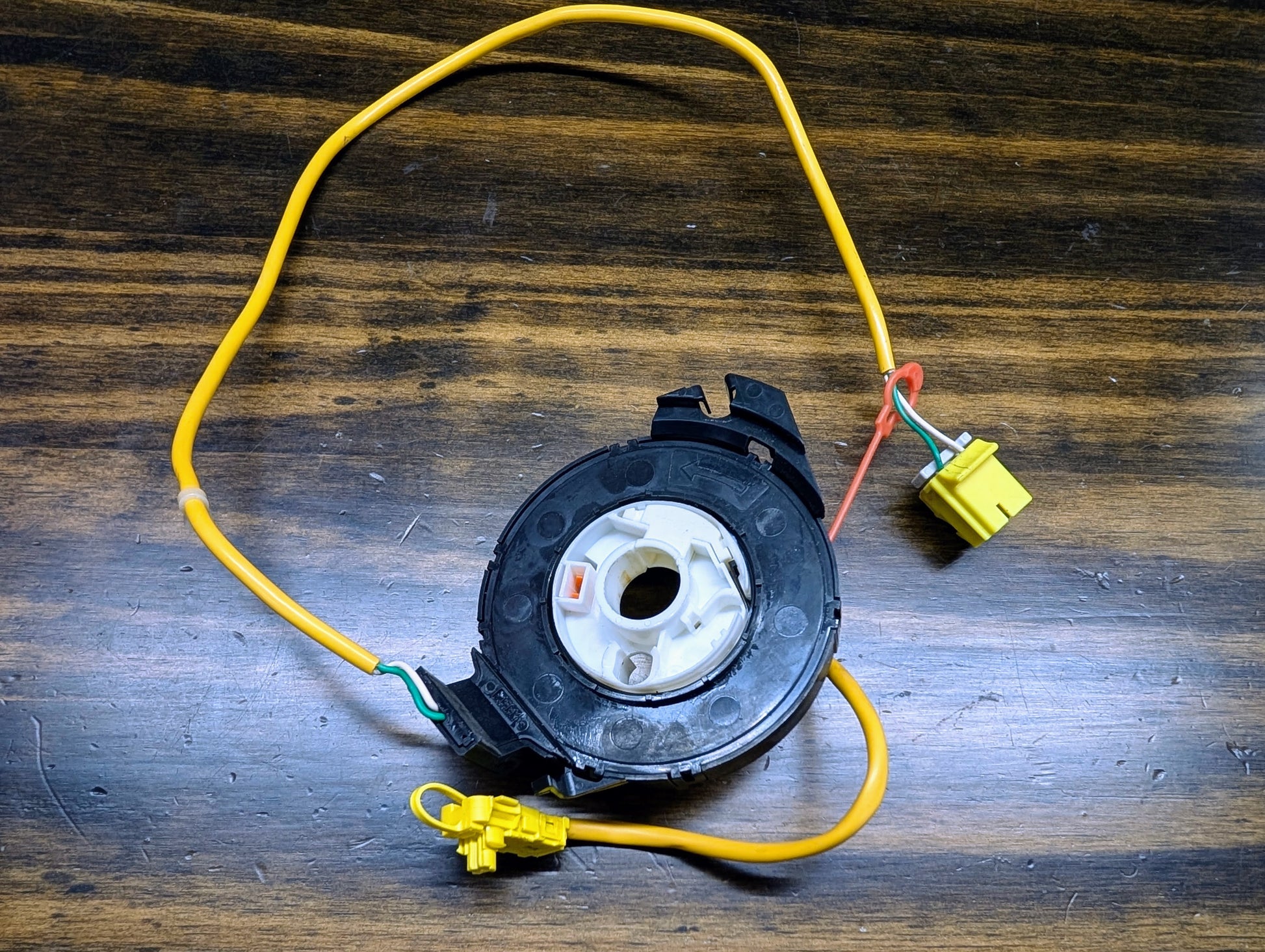 A General Motors OEM Steering Wheel Air Bag SRS Clock Spring, tested for 2004-2005 Chevy S10 Blazer and more, is shown on a wooden surface.