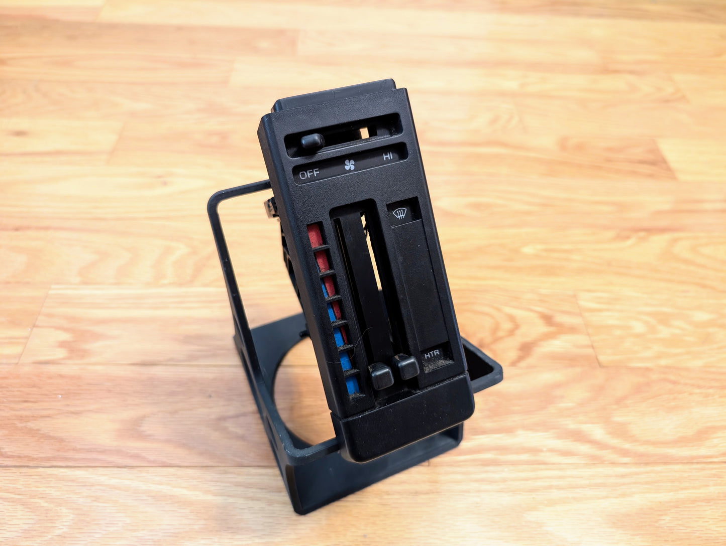 A RARE General Motors OEM HVAC Heater Control Panel (NO A/C, NO Vent) for 1986–1994 Chevrolet S10, Blazer & more stands upright on a smooth light wood floor. Features sliders for temperature and fan speed.