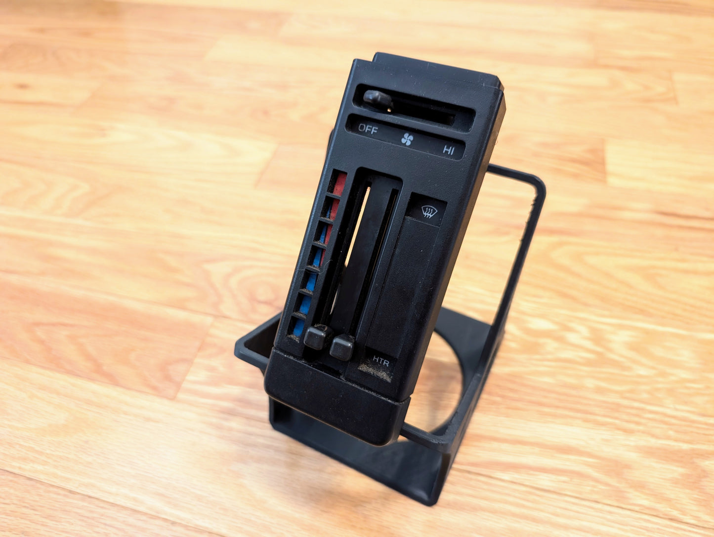 A RARE General Motors HVAC Heater Control Panel OEM (no A/C, no vent) for 1986-1994 Chevrolet S10, Blazer, and more is shown upright on a wooden floor.