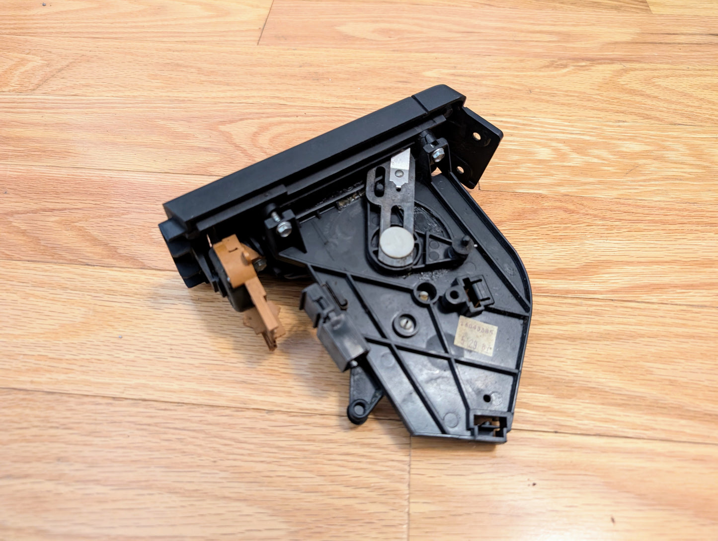 A black plastic and metal General Motors RARE HVAC Heater Control Panel OEM (no A/C, no vent) for 1986–1994 Chevrolet S10, Blazer, and more, sits on a wooden floor.