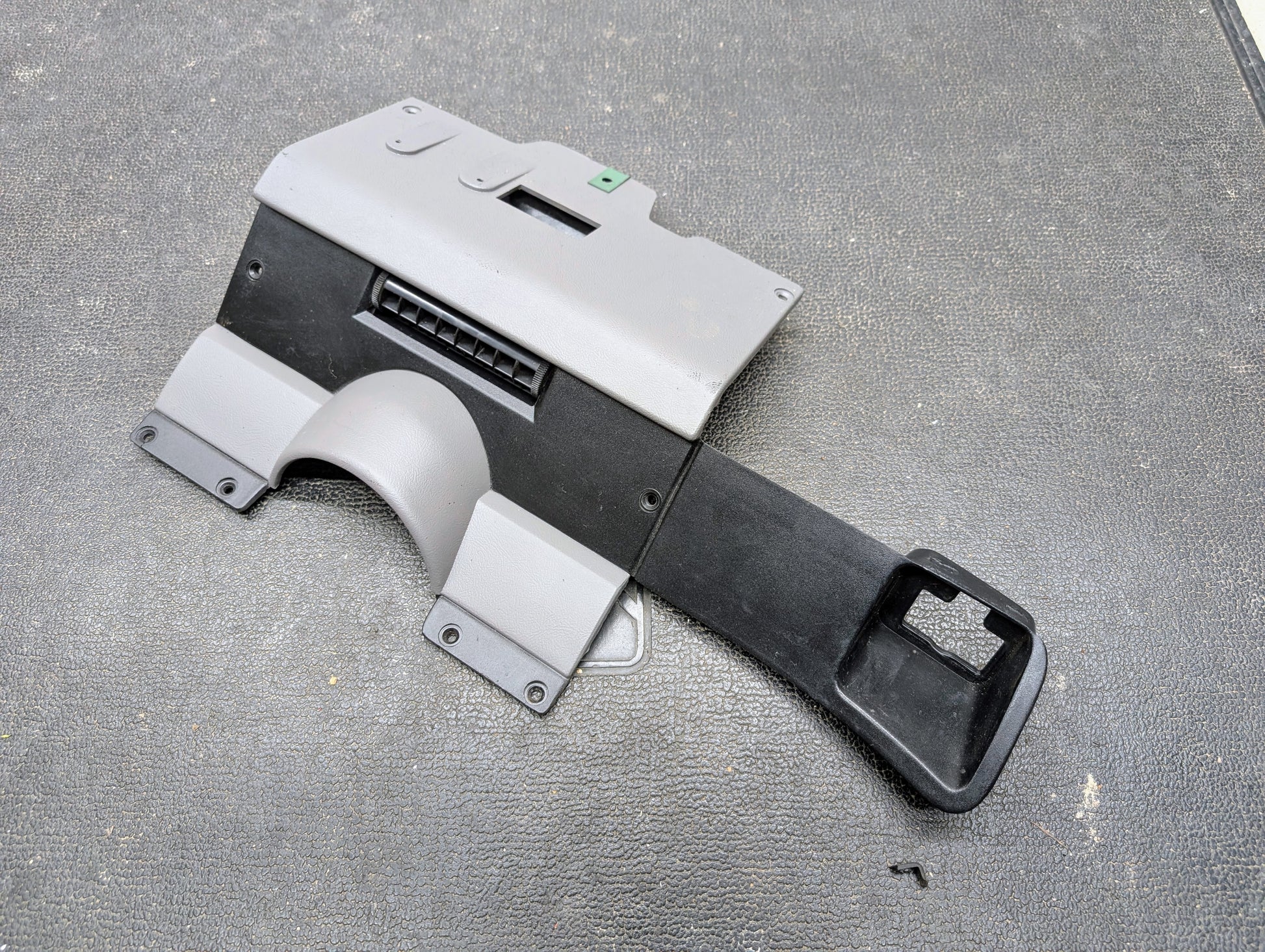 A General Motors OEM Lower Dash Trim Knee Bolster in Lt Gray for 1986-1993 Chevy S10 Blazer/GMC S15, featuring a vent opening and contours, is shown on a textured black surface.
