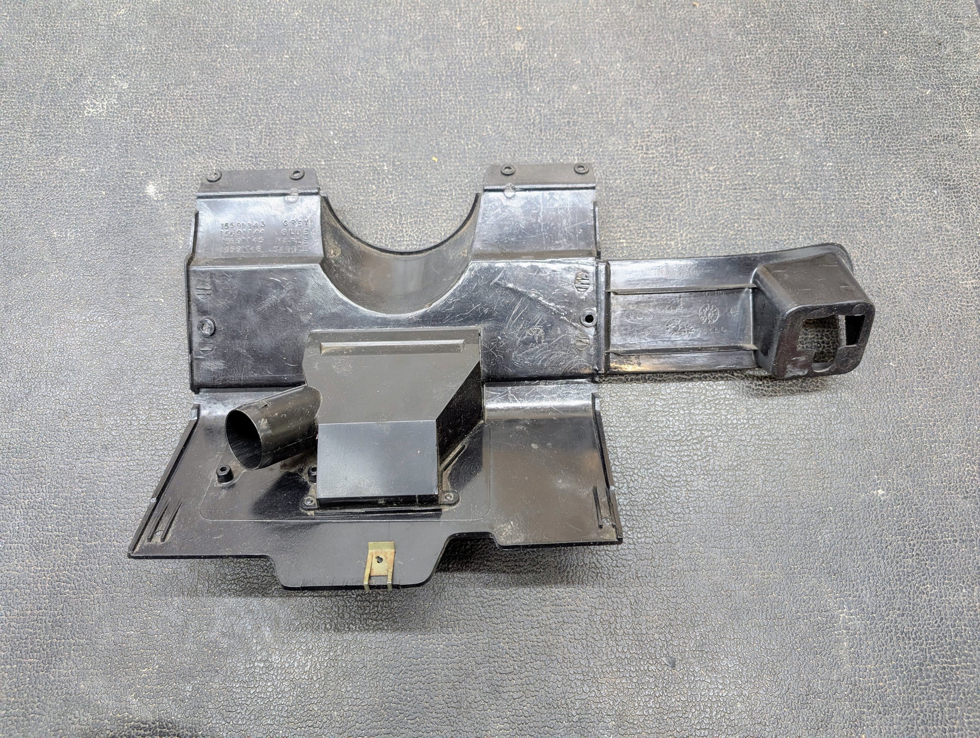 A General Motors OEM Lower Dash Trim Knee Bolster in dark gray for 1986-1993 Chevy S10, Blazer, GMC S15 and more, featuring multiple compartments and mounting points, is shown on a textured dark surface.