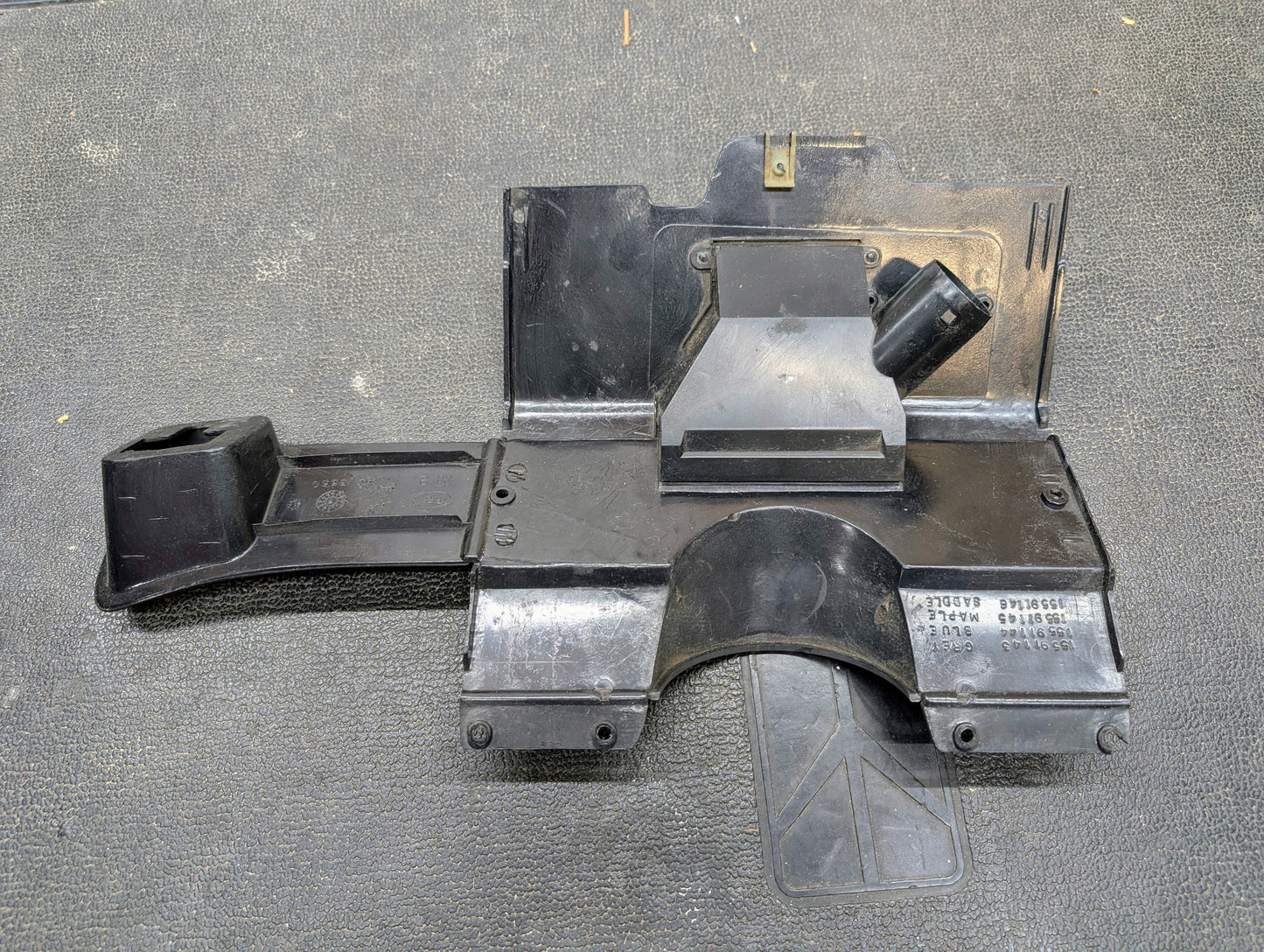 A General Motors OEM Lower Dash Trim Knee Bolster in dark gray for 1986-1993 Chevy S10, Blazer, GMC S15, and more features molded compartments and labels, angled sections, a tube, and stamped ID numbers like 15591143.