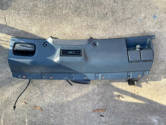 General Motors Lower Dash Trim Knee Bolster in Blue for 1995–1997 Chevy S10 Blazer, featuring air vents and a glove compartment, shown detached on concrete with visible shadows and minor debris.