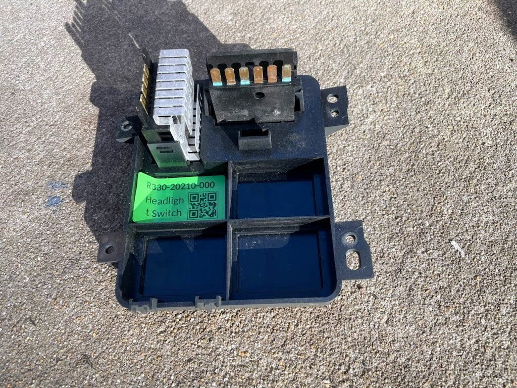 A close-up of a General Motors OEM Headlight Headlamp Switch for 1994-1997 Chevy S10, Blazer, GMC Sonoma, and Jimmy with visible connectors shows the module resting on rough concrete.
